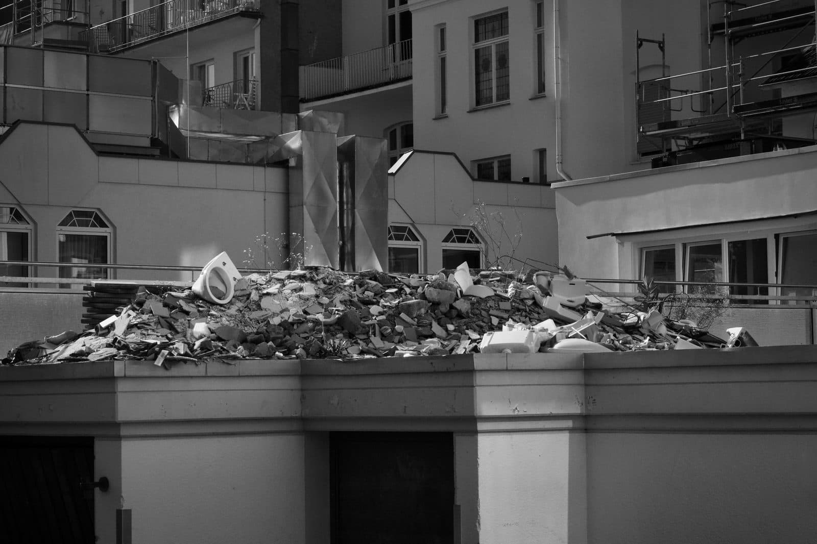 Tas de gravats et débris de chantier, dont un lavabo, entassés sur une terrasse d'immeuble en travaux