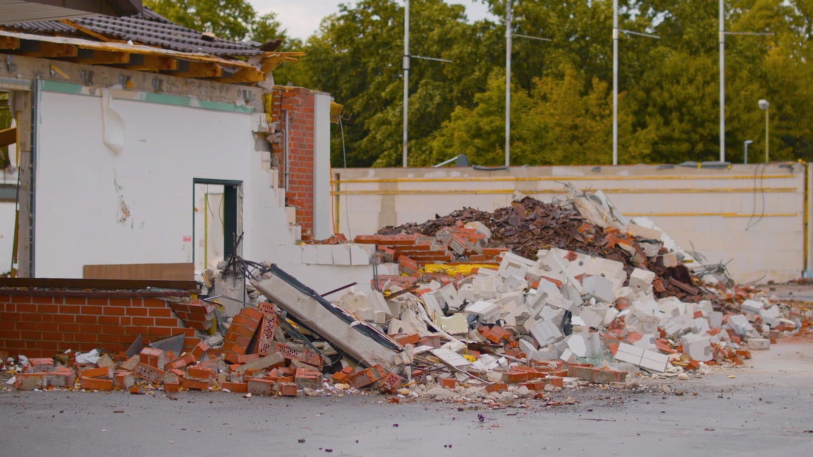 Bâtiment en cours de démolition avec un tas de gravats, briques et tuiles triés sur le chantier