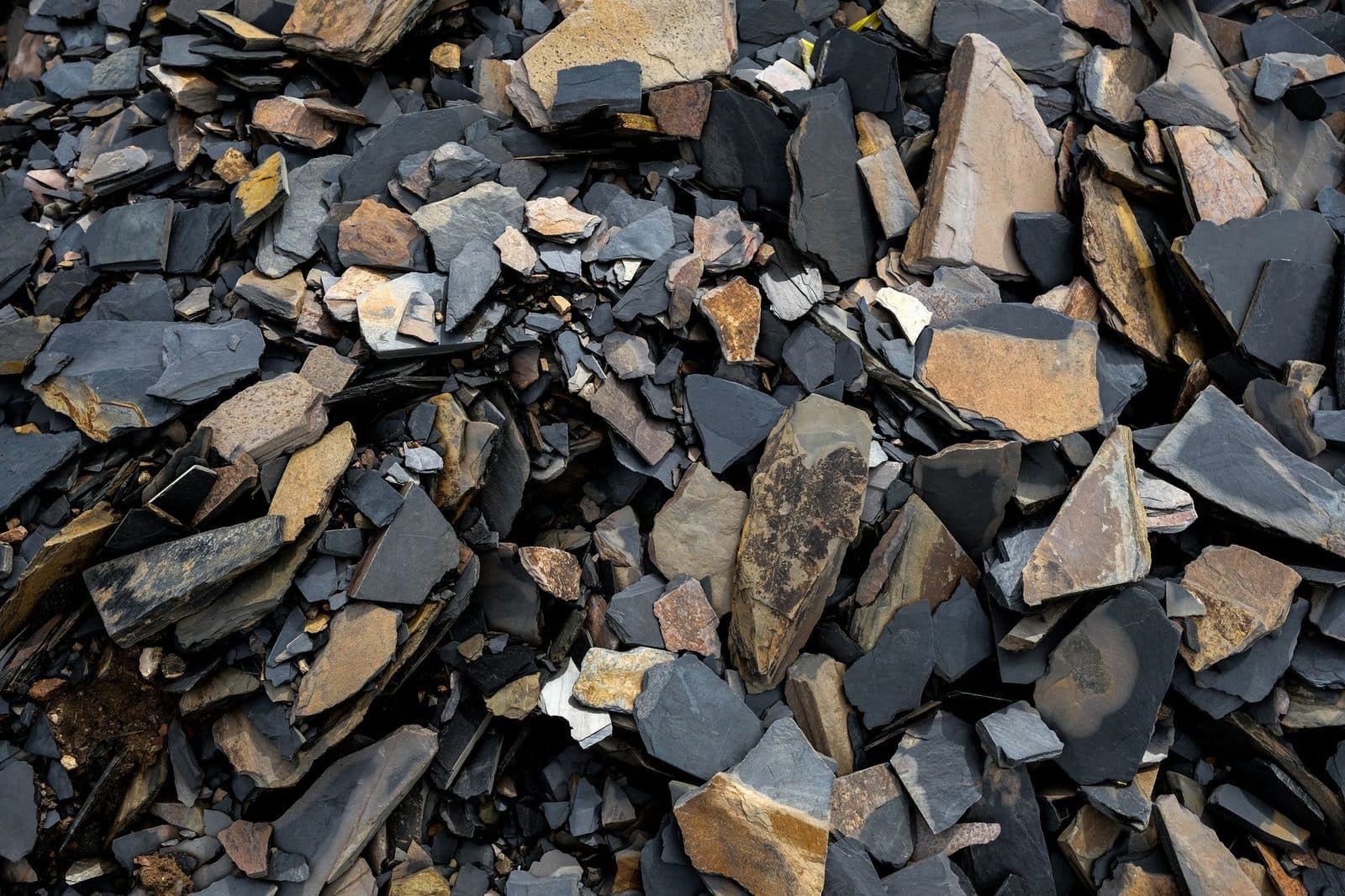 Tas de gravats : fragments de pierres et d'ardoises grises et ocres empilés en vrac