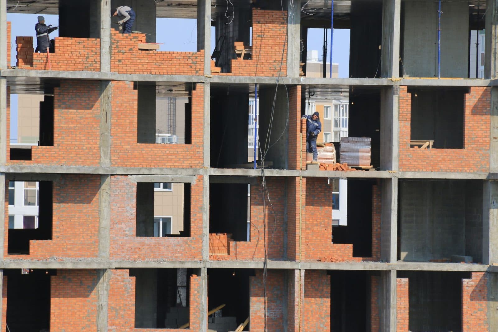Ouvriers montant des murs en briques sur un immeuble en construction avec structure en béton