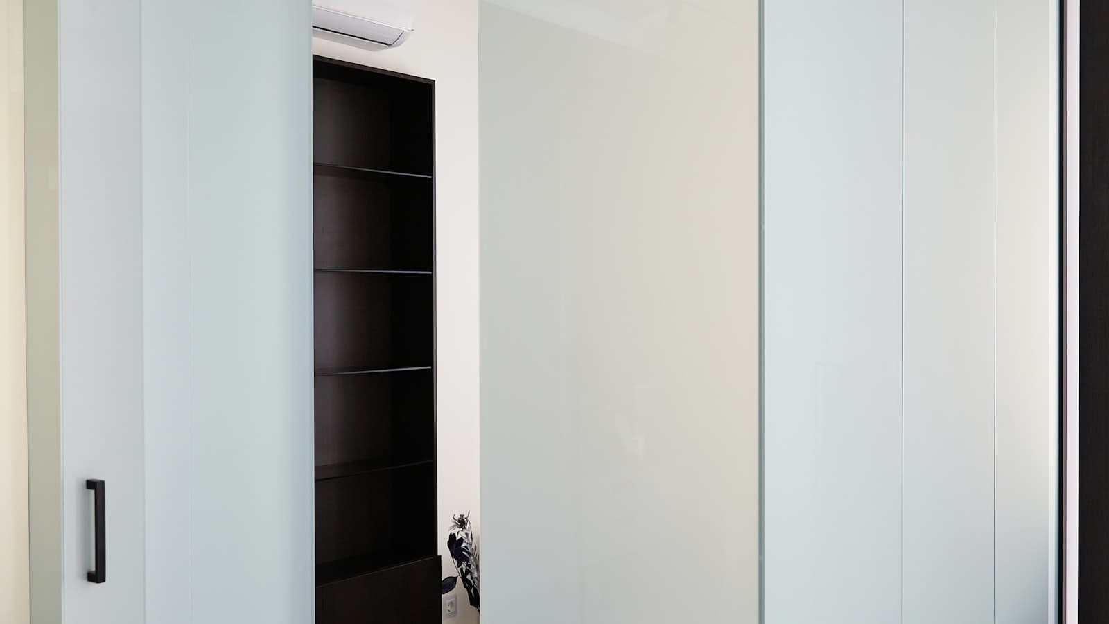 Verrière d'atelier à cadre noir séparant deux pièces d'un intérieur lumineux
