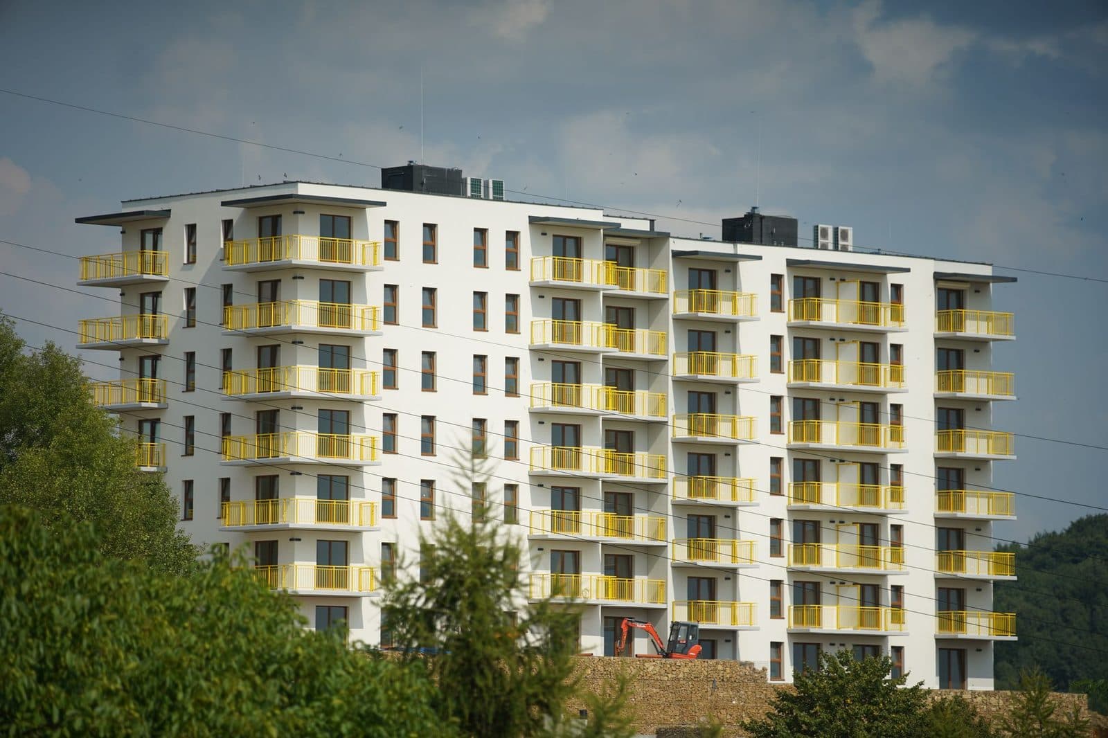 Immeuble résidentiel neuf aux balcons jaunes avec une mini-pelle sur le chantier en contrebas