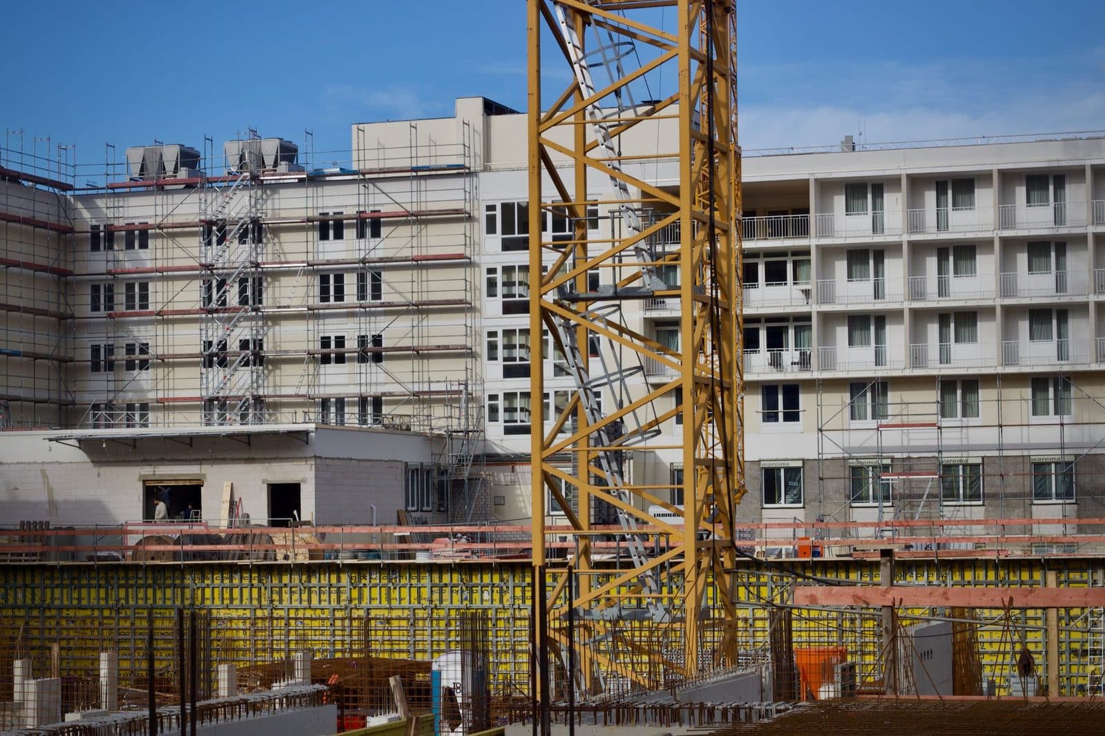 Chantier de construction d'immeubles résidentiels avec grue jaune, échafaudages et coffrages