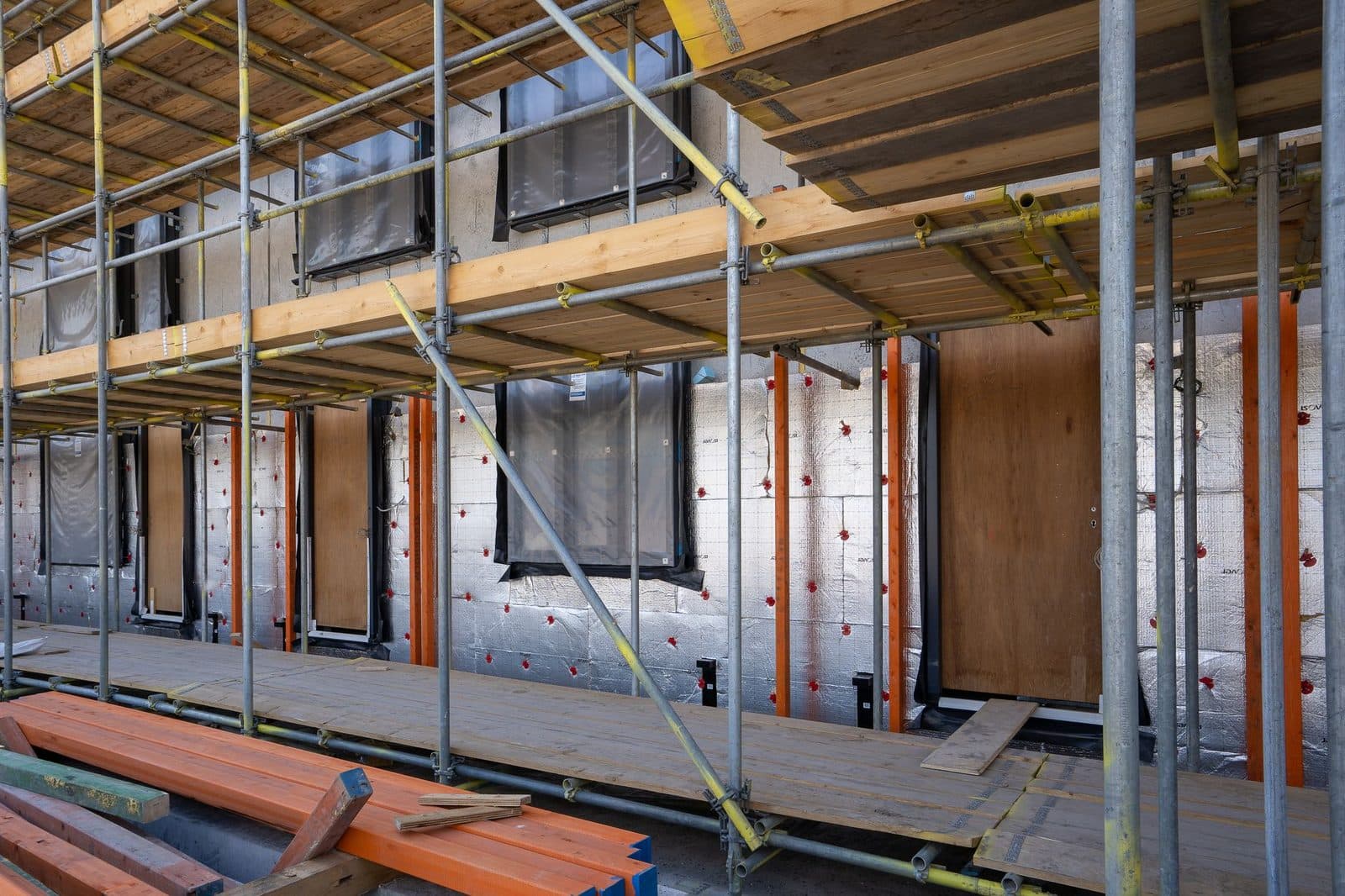 Façade d'immeuble en rénovation avec échafaudage, isolation extérieure et pare-vapeur autour des fenêtres