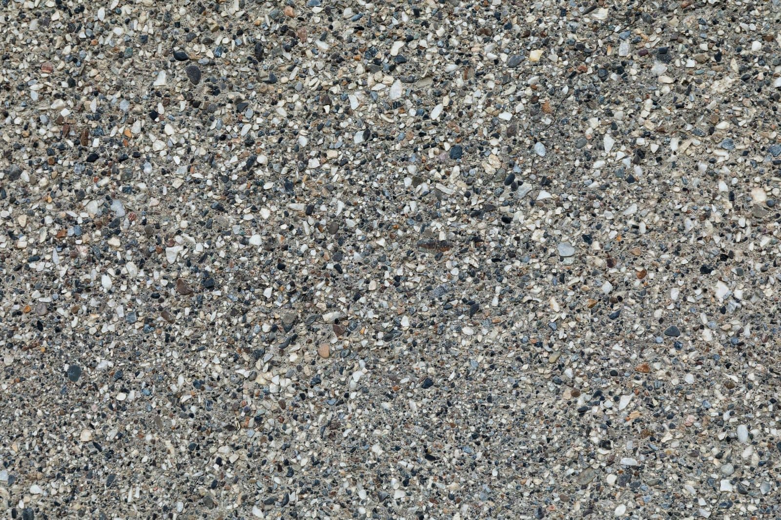 Gros plan d'une surface en béton granuleux avec des agrégats de pierres multicolores.