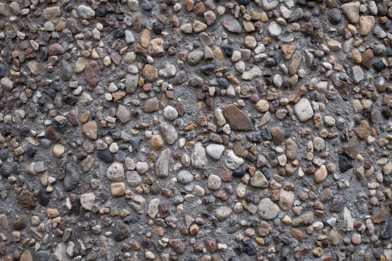 Gros plan d'une surface en béton aggregate composé de petits cailloux et de graviers multicolores.