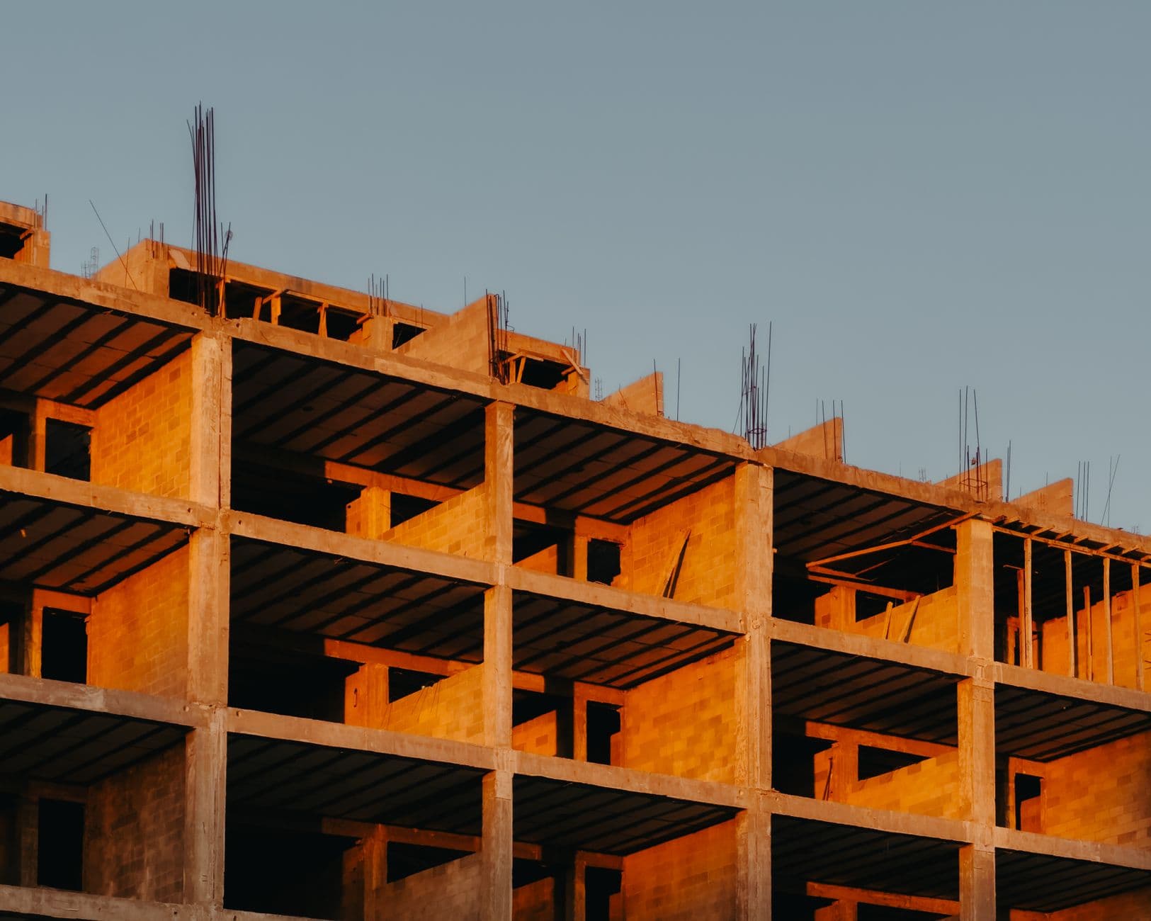 Immeuble d'habitation en construction, structure béton et murs en briques, au coucher du soleil