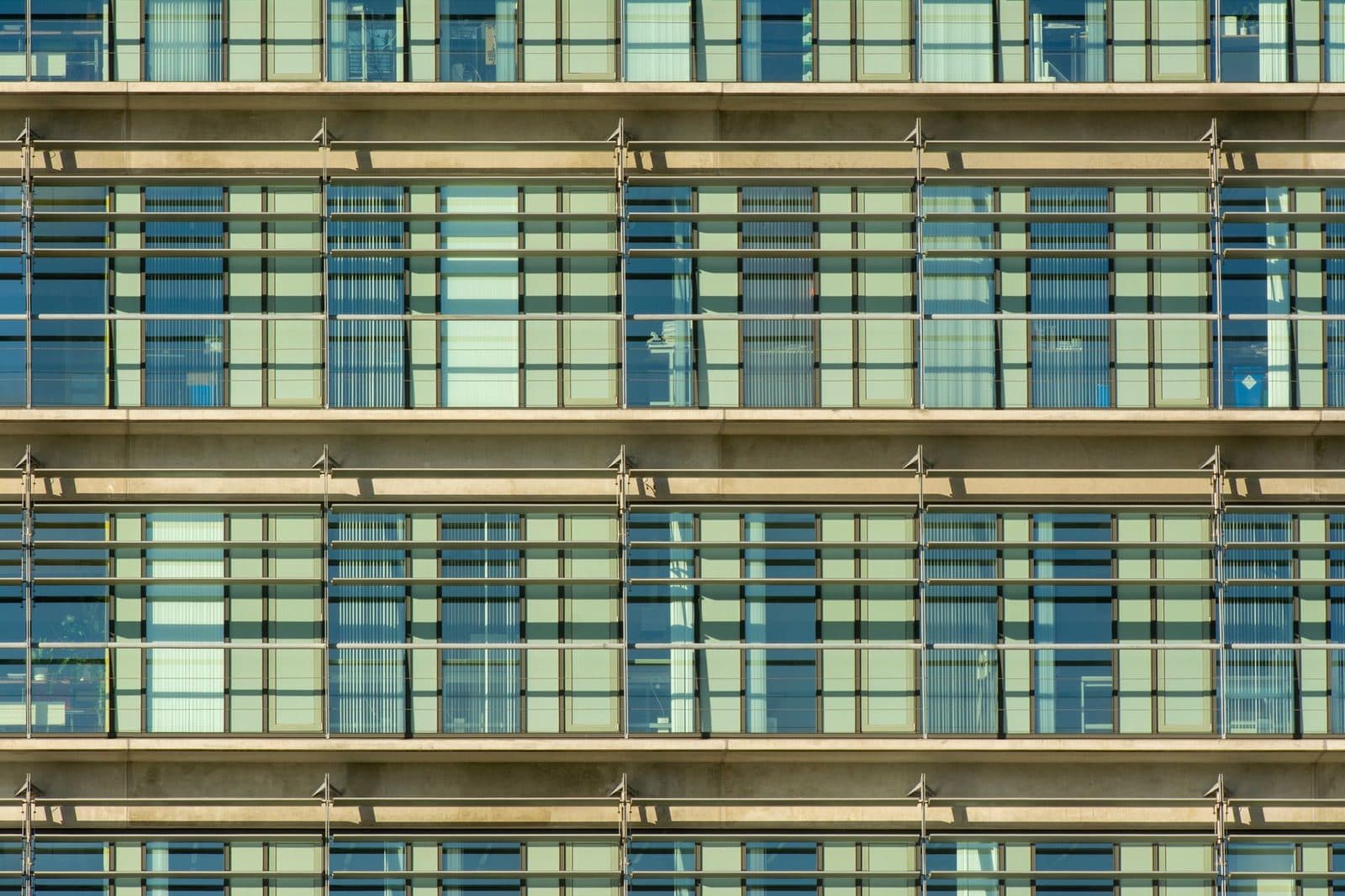 Façade vitrée d'un immeuble moderne avec balcons et garde-corps métalliques sur plusieurs étages