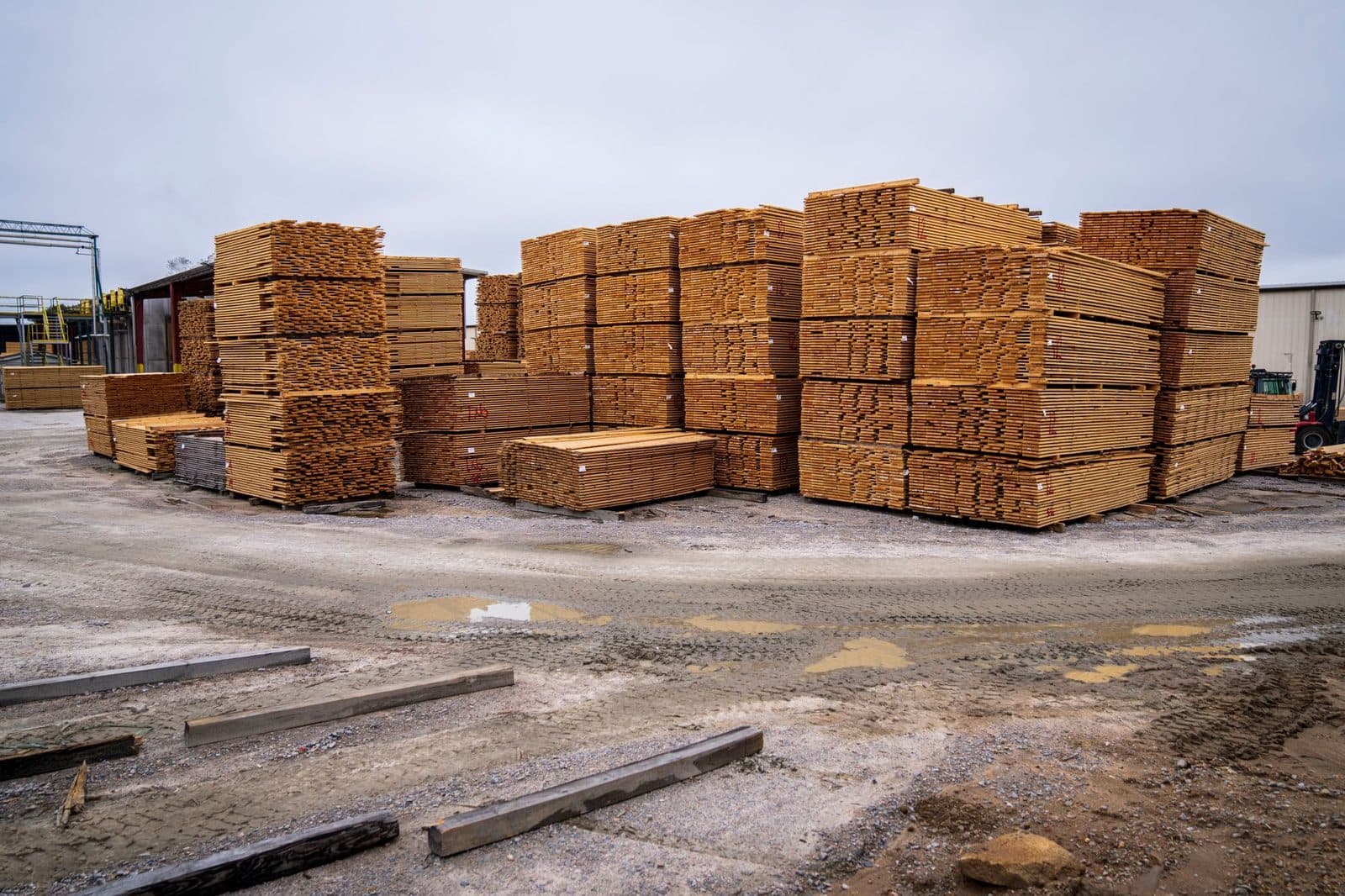 Piles de planches de bois stockées sur un terrain extérieur d'une aire de stockage de matériaux