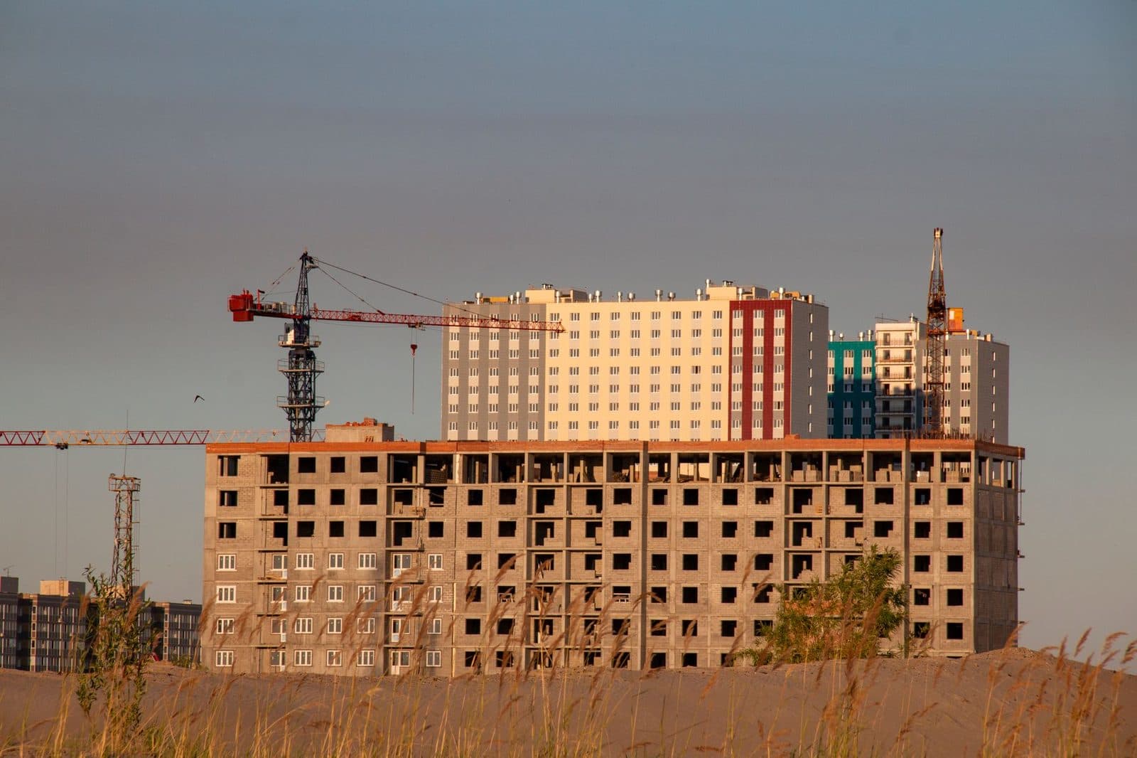 Immeubles résidentiels en construction avec grues sur un chantier au coucher du soleil