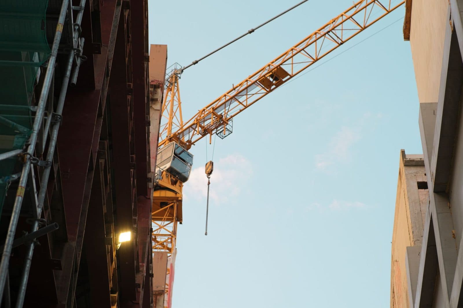 Grue de chantier jaune entre deux bâtiments en construction avec échafaudages, vue en contre-plongée