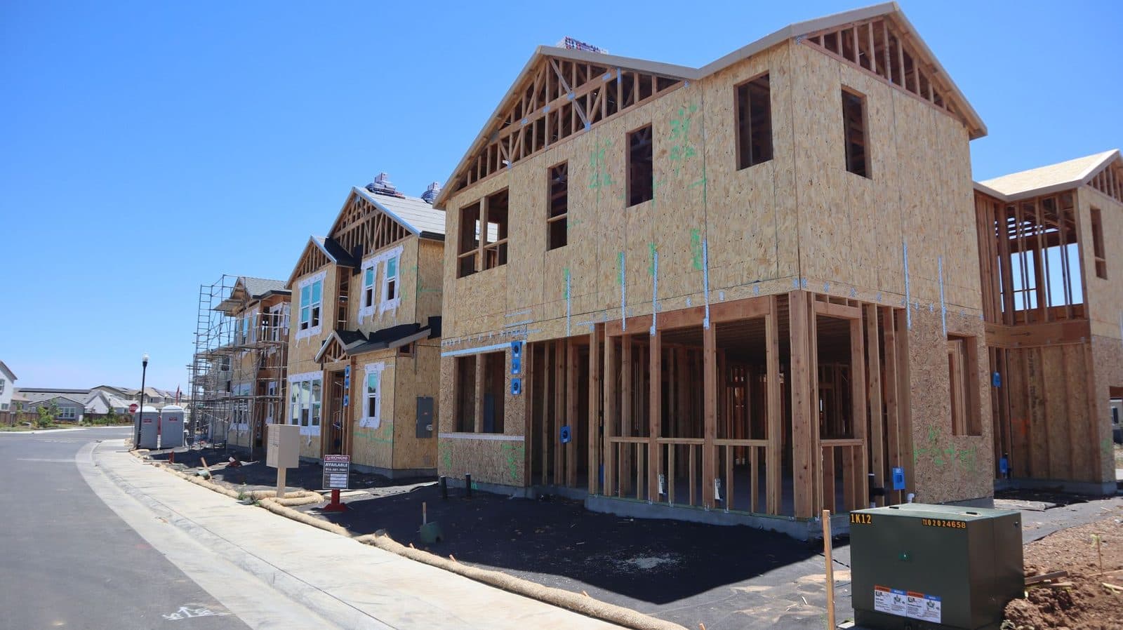 Maisons neuves en construction à ossature bois avec échafaudages le long d'une rue résidentielle