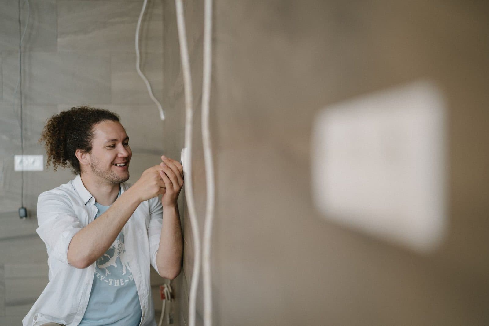 Homme souriant appliquant un enduit sur un mur pendant des travaux de rénovation intérieure