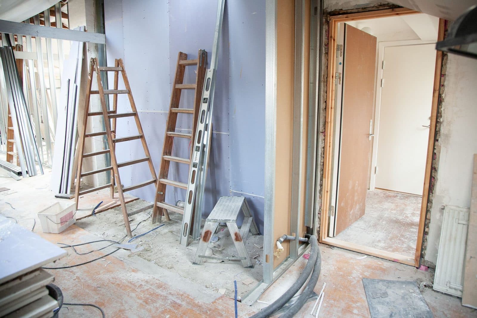 Chantier de rénovation intérieure : cloisons en plaques de plâtre, échelles, rails métalliques et radiateur démonté
