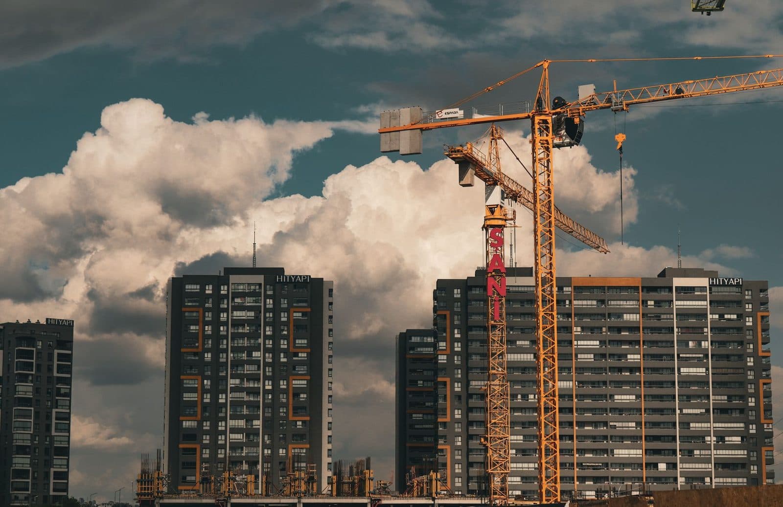 Grue jaune sur un chantier de construction d'immeubles résidentiels de grande hauteur sous un ciel nuageux