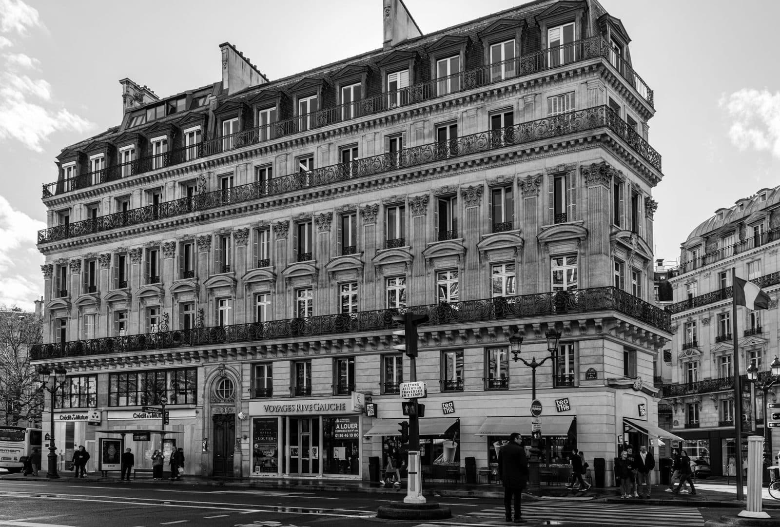 Immeuble haussmannien parisien en pierre de taille avec balcons en fer forgé et commerces en rez-de-chaussée