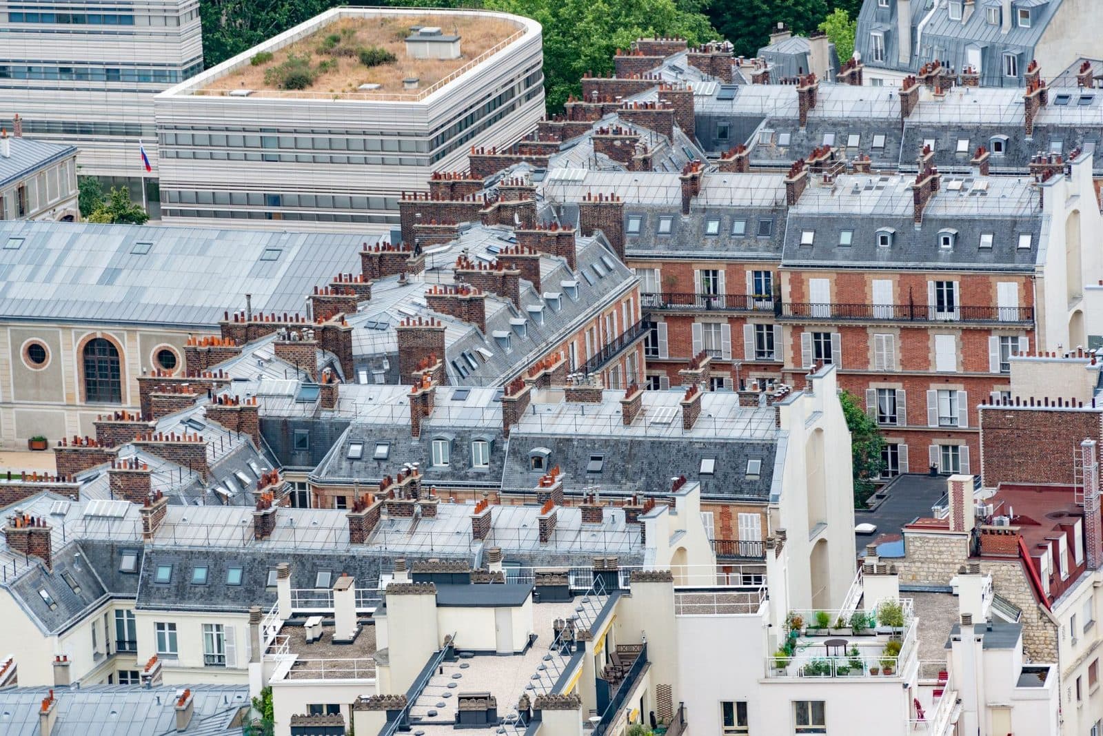 Vue aérienne des toits en zinc et façades d'immeubles haussmanniens parisiens avec cheminées en brique
