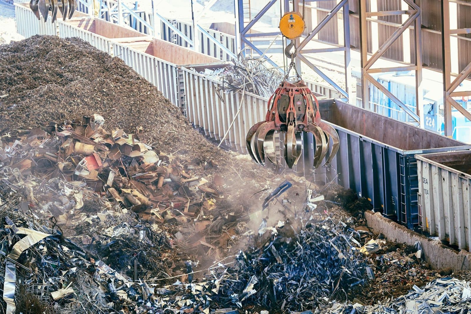 Grappin de grue déchargeant des déchets métalliques sur un site de recyclage, bennes et tas de ferraille