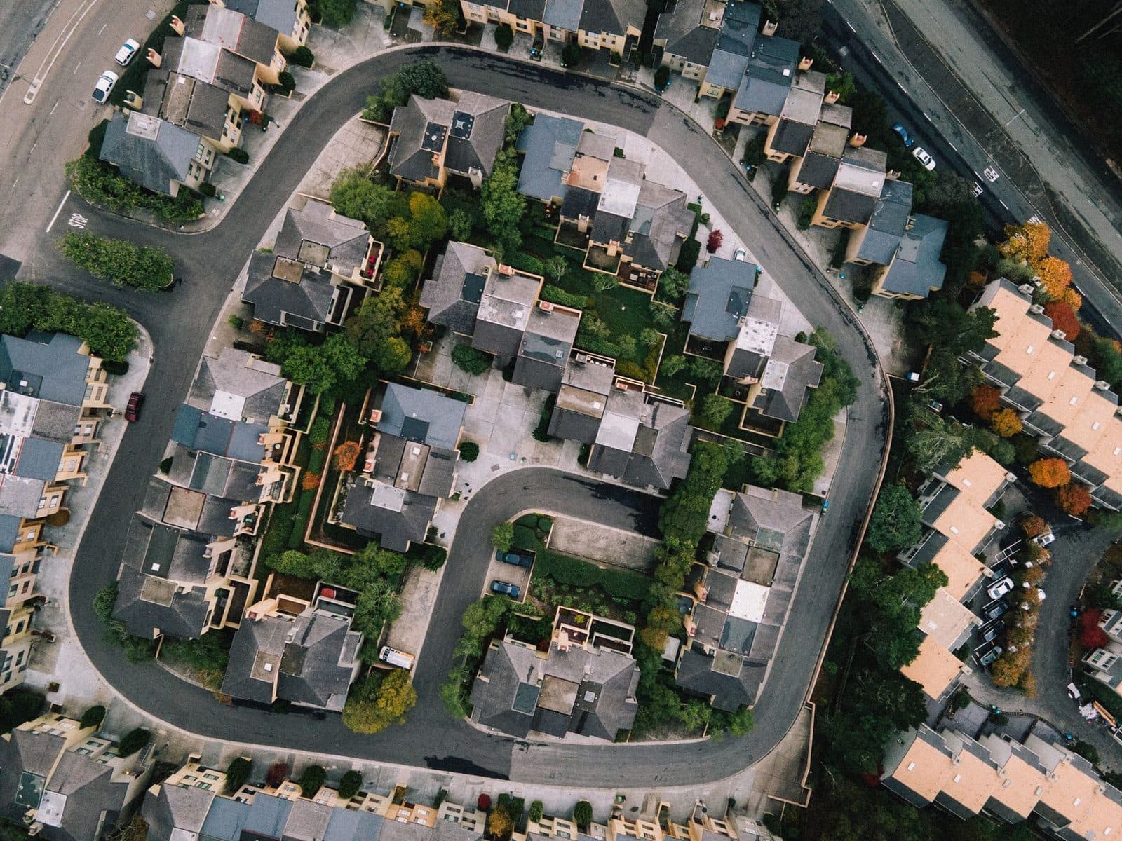 Vue aérienne d'un quartier résidentiel avec maisons, immeubles, rue en boucle et arbres