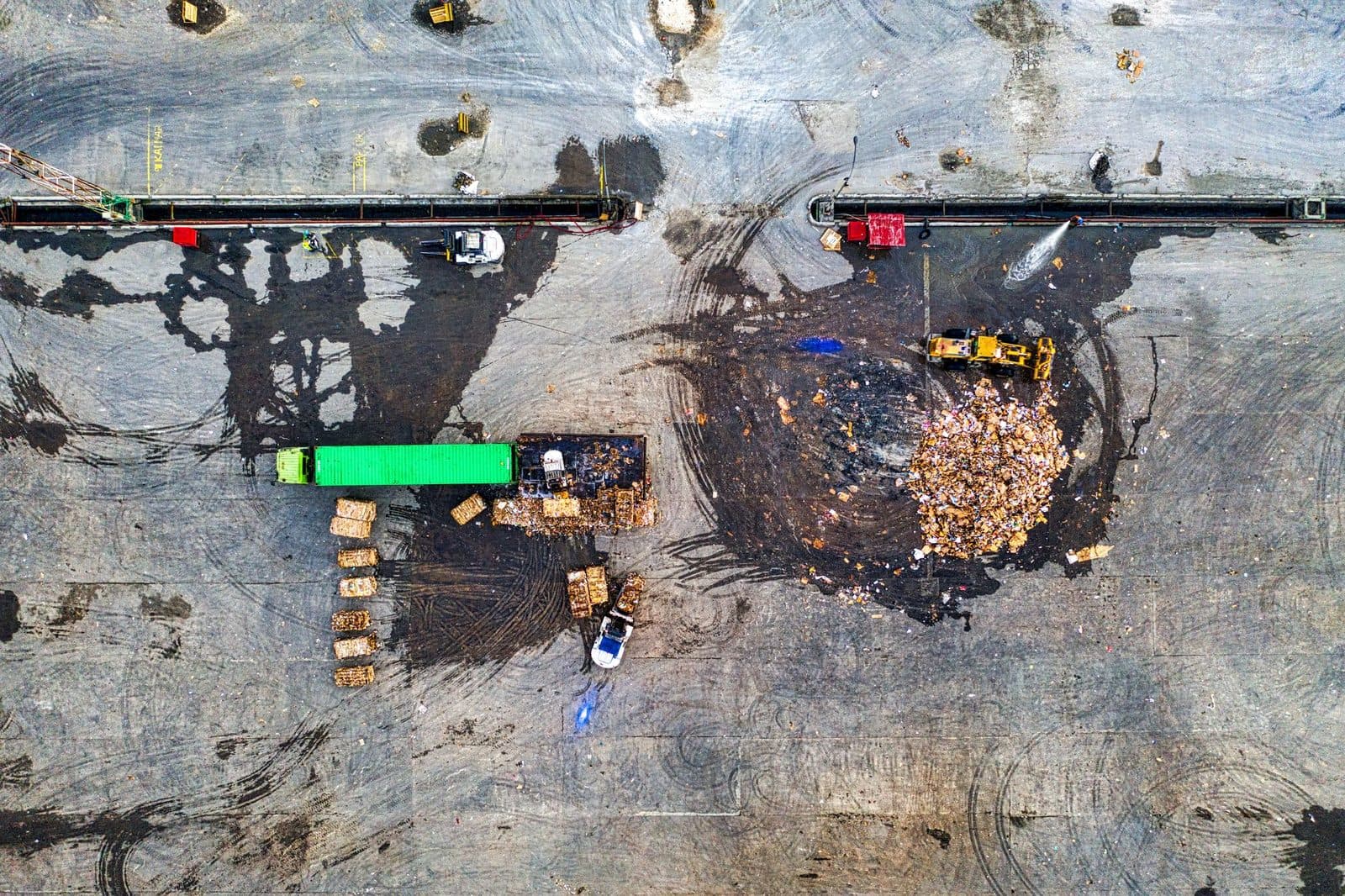 Vue aérienne d'une plateforme de tri de déchets avec camion, chargeuse, tas de gravats et bois