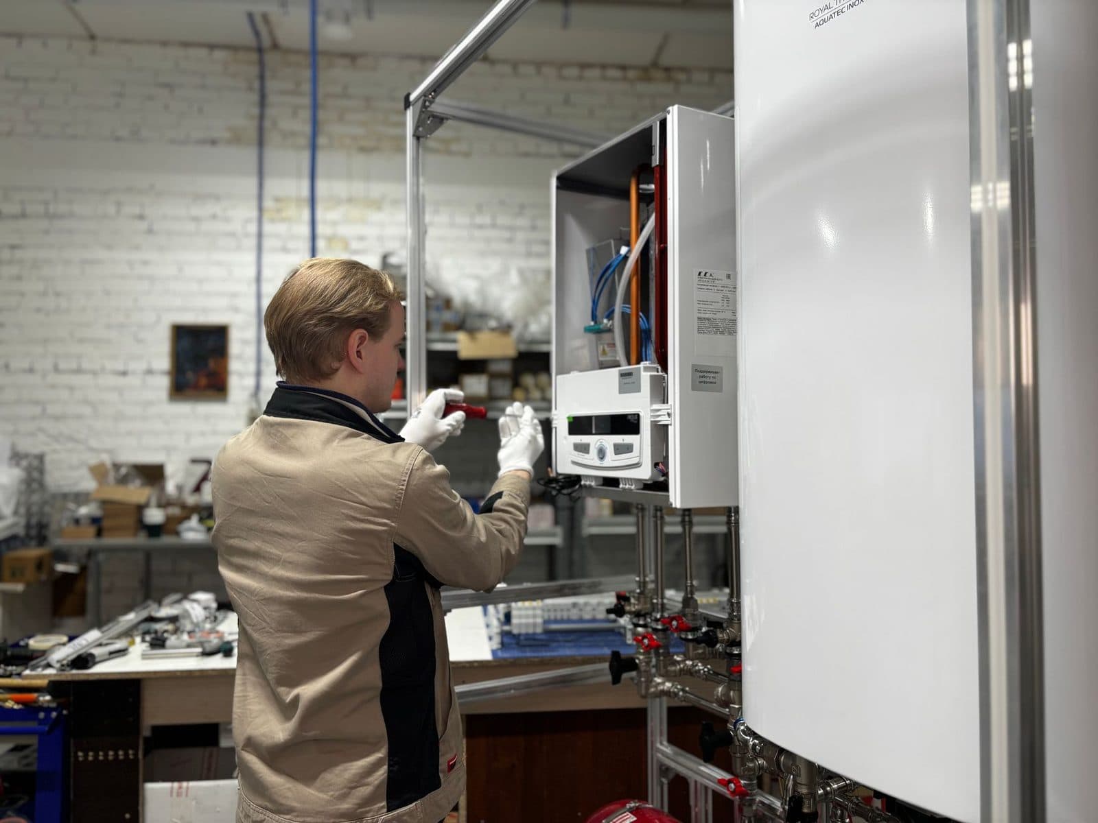 Un technicien travaillant sur une chaudière à gaz blanche dans un atelier.