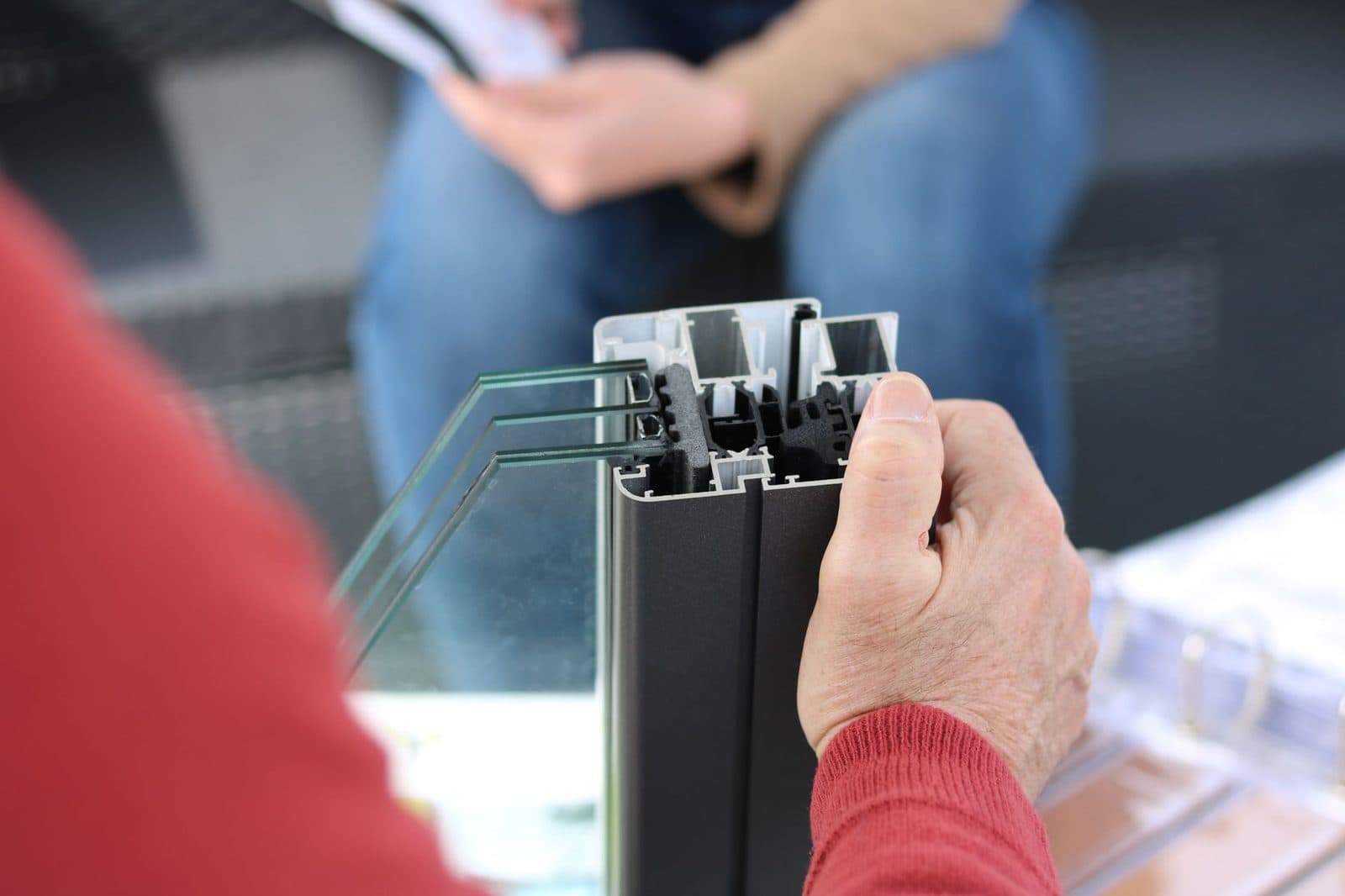 Mains tenant une coupe de profilé de fenêtre en aluminium avec double vitrage lors d'un rendez-vous conseil