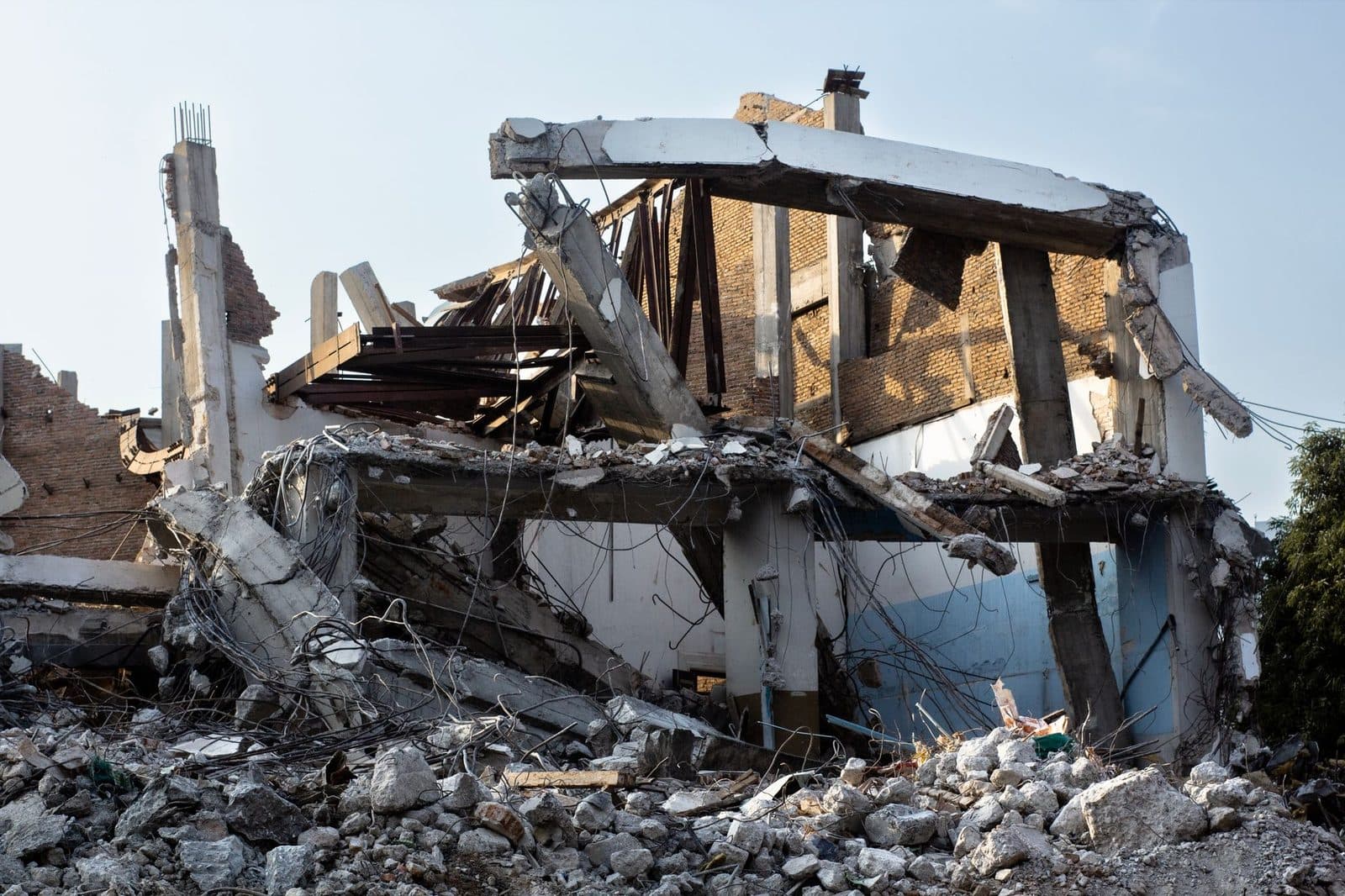 Bâtiment en cours de démolition avec dalles de béton effondrées, ferraille apparente et gravats au premier plan
