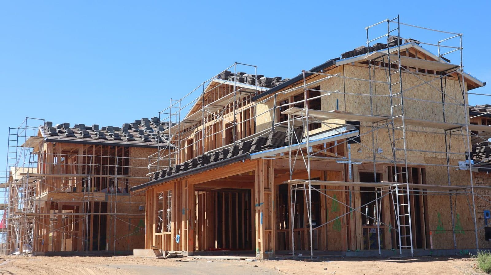 Maisons en construction à ossature bois entourées d'échafaudages sous un ciel bleu